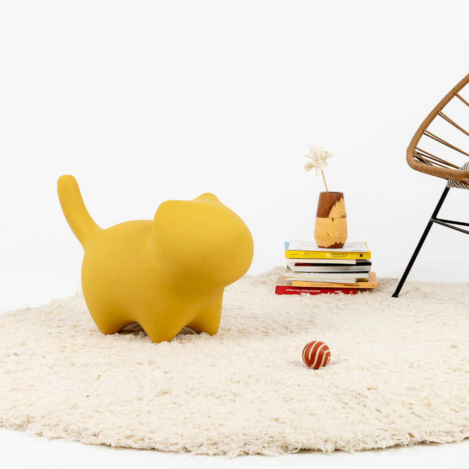 Figura decorativa de gato minimalista utilizada como puf en amarillo